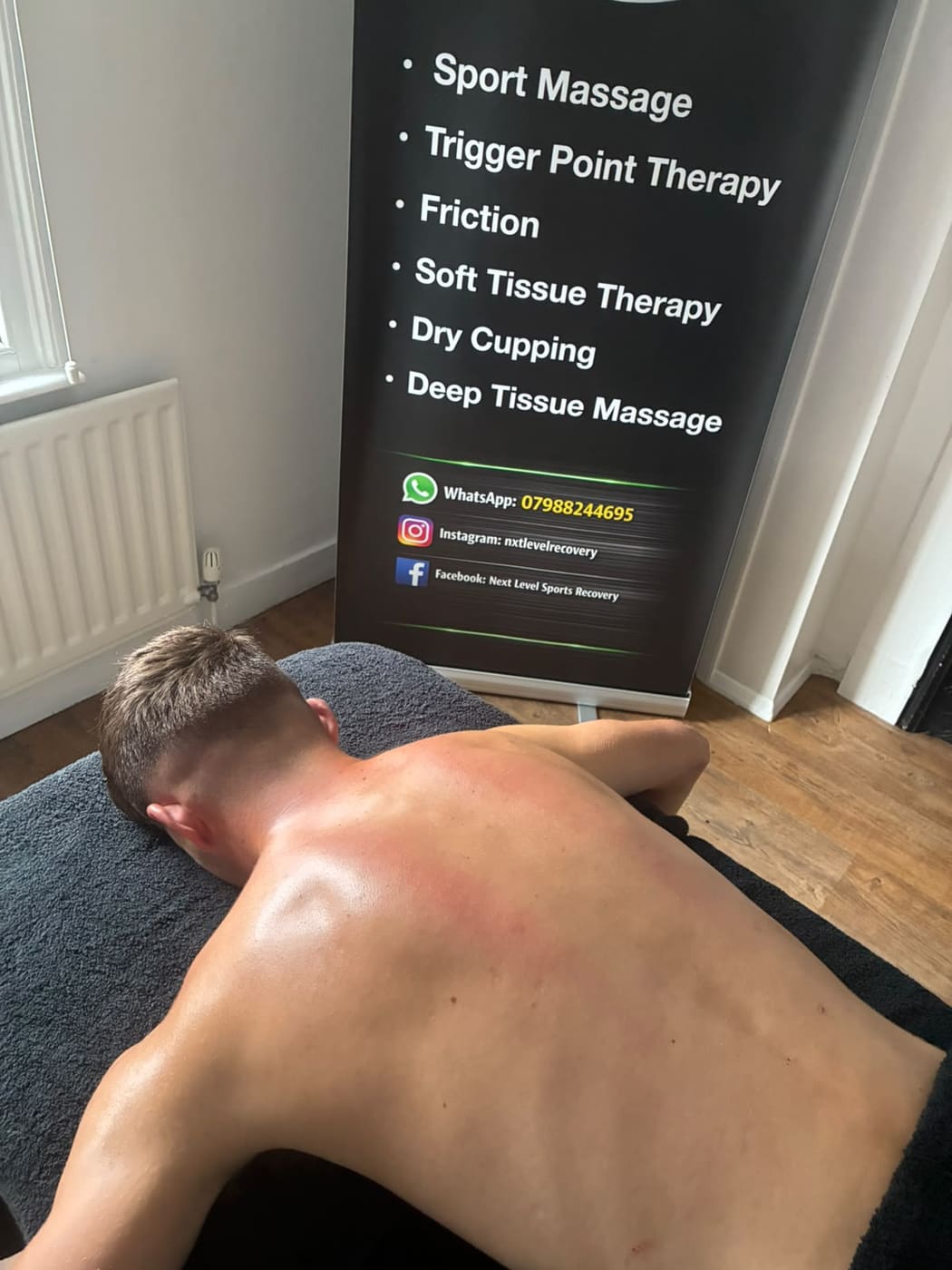 Sports massage in the treatment room, with the Next Level banner behind